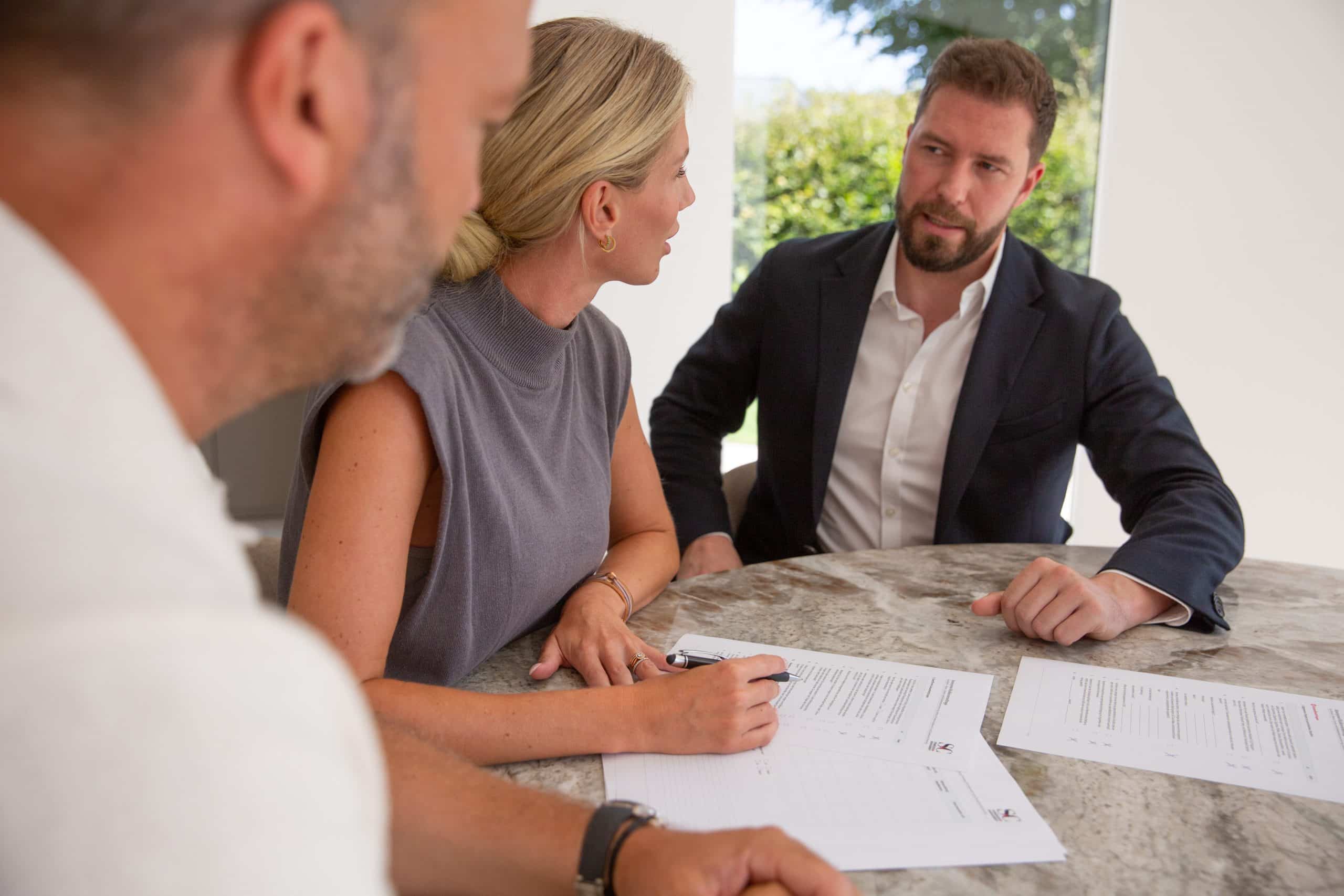 Beratungsgespräch mit zwei Kunden am Tisch: gemeinsam finanzielle Fragen besprechen.